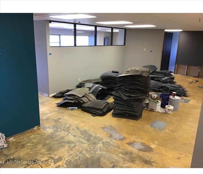 Commercial office space with carpet ripped out and office chairs in center